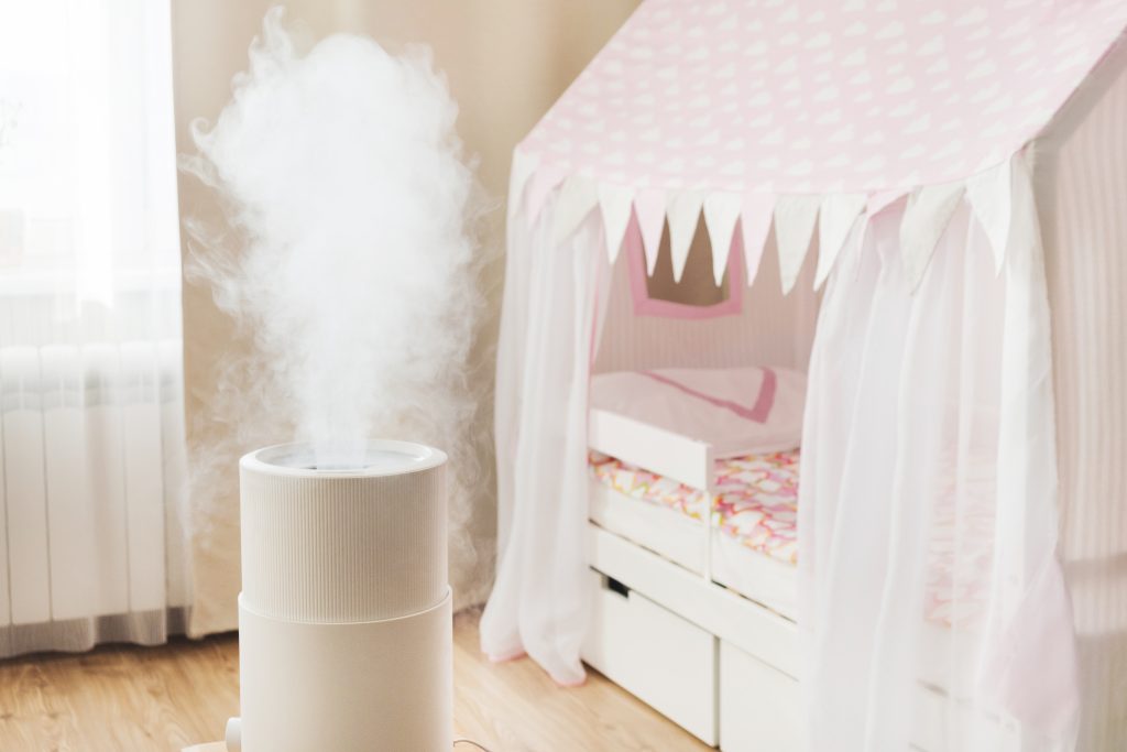 White humidifier misting in a cosy kids’ room with soft lighting, wooden floor and a pink play tent over the bed—toddler tips inspired.
