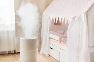 White humidifier misting in a cosy kids’ room with soft lighting, wooden floor and a pink play tent over the bed—toddler tips inspired.