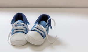 Blue and white baby sneakers with white laces, one untied, side by side—ideal for newborn essentials Australia.