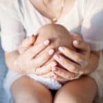 Mother resting gently with her newborn during the fourth trimester