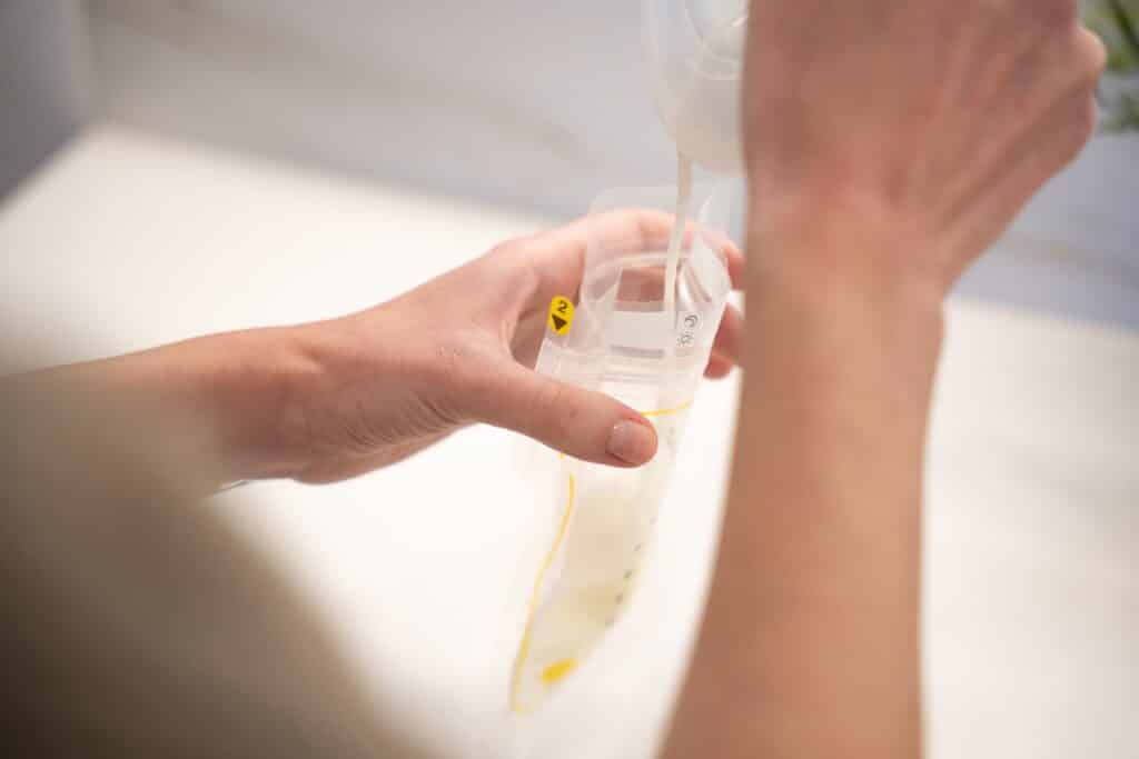 Mum expressing breast milk into a storage bag, a key step when learning how to increase milk supply